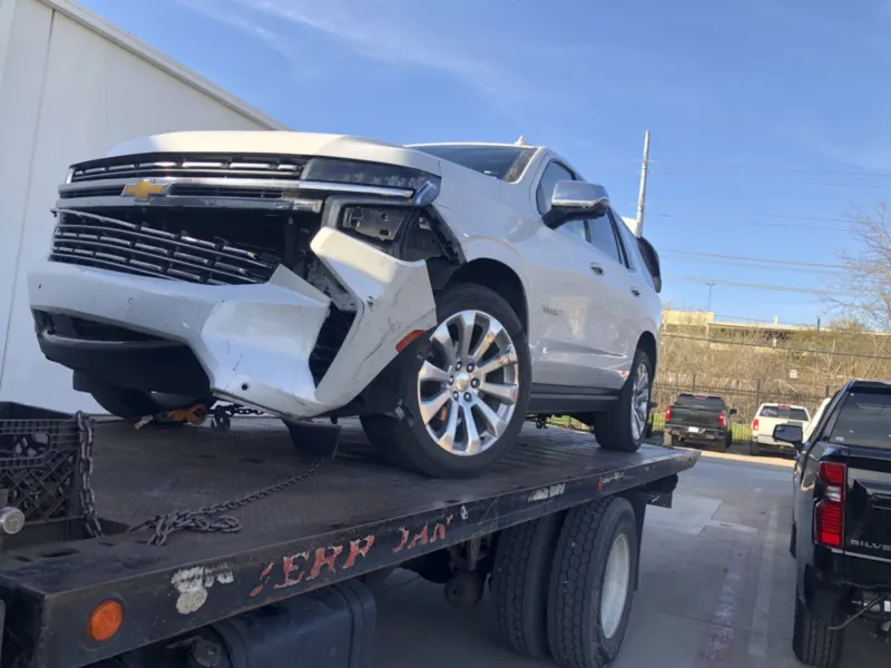 Chevrolet Tahoe with front-end damage on a Dallas Towing Company flatbed