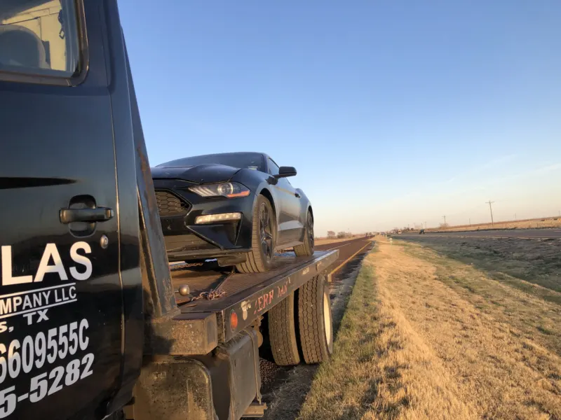 Dallas Towing Company flatbed stopped on the highway shoulder