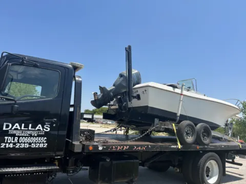 Boat and trailer on a Dallas Towing Company flatbed