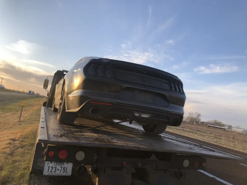 Ford Mustang on a flatbed during a long distance tow from Dallas