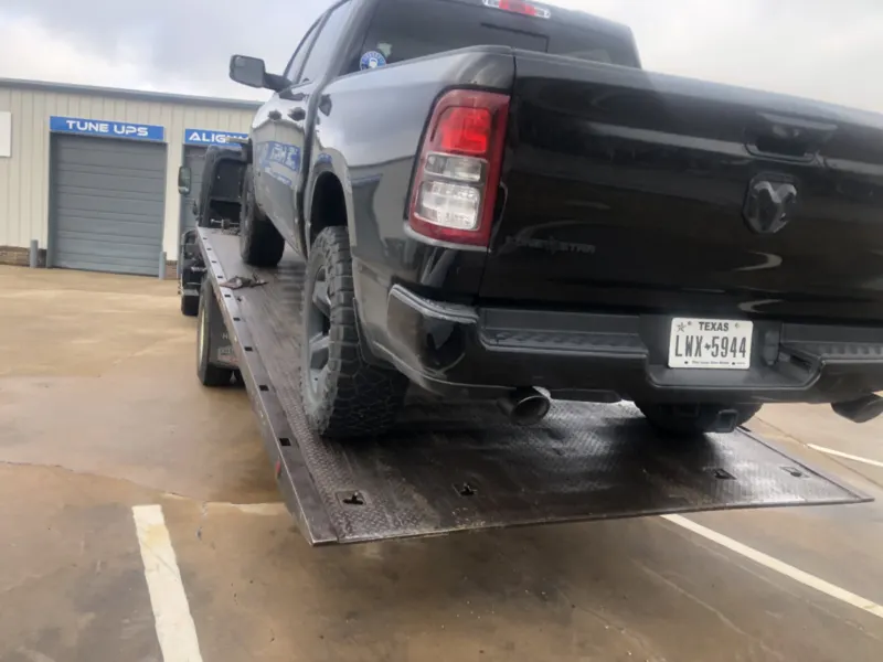 Ram pickup on a Dallas Towing Company flatbed at a Dallas shop